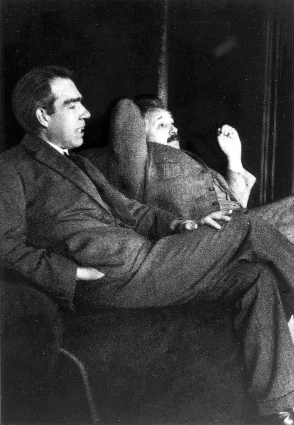 Bohr and Einstein seated indoors, Bohr talking and gesturing, Einstein listening.