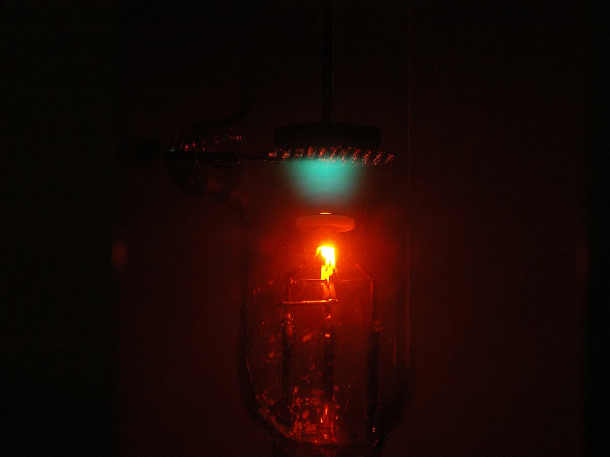 A Franck–Hertz tube filled with neon, glowing in several distinct orange bands separated by dark gaps.