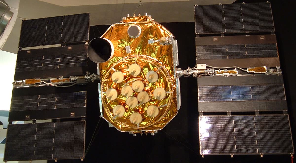A GPS satellite in orbit, solar panels extended, Earth below.