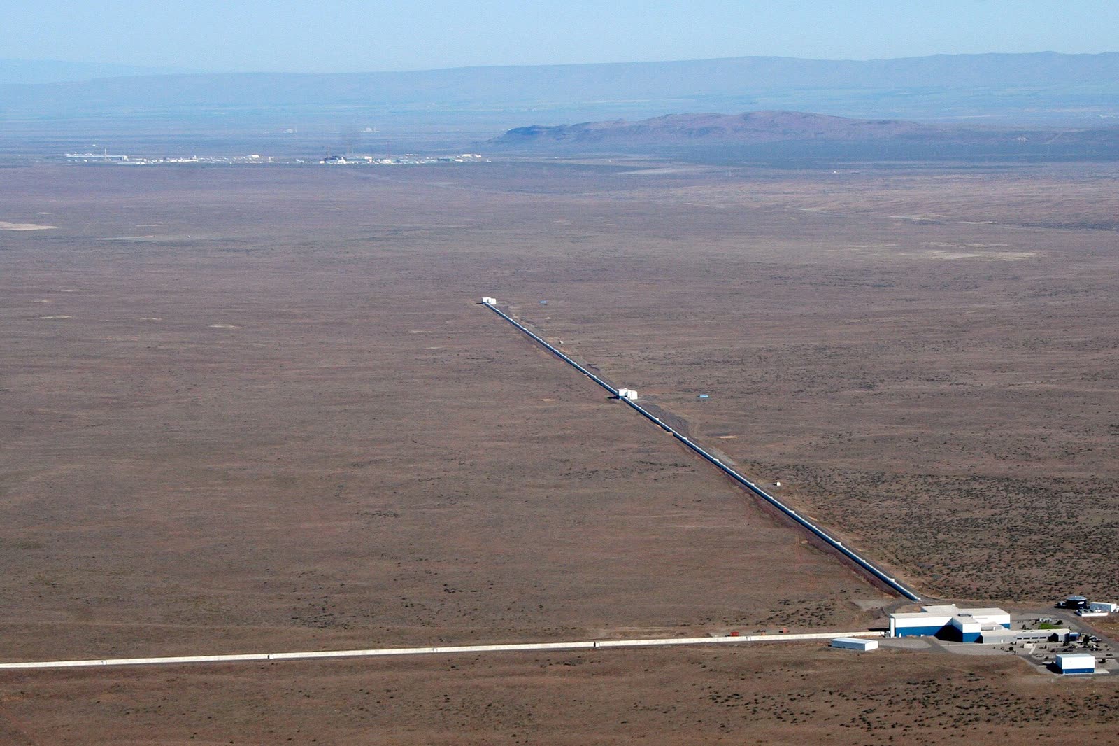 Aerial view of LIGO Hanford: two concrete arms running four kilometres each at right angles across flat desert.