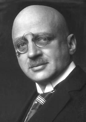 A photographic portrait of Fritz Haber in middle age: bald, wearing pince-nez spectacles, a moustache, a dark suit and a striped tie, turned slightly to his right.