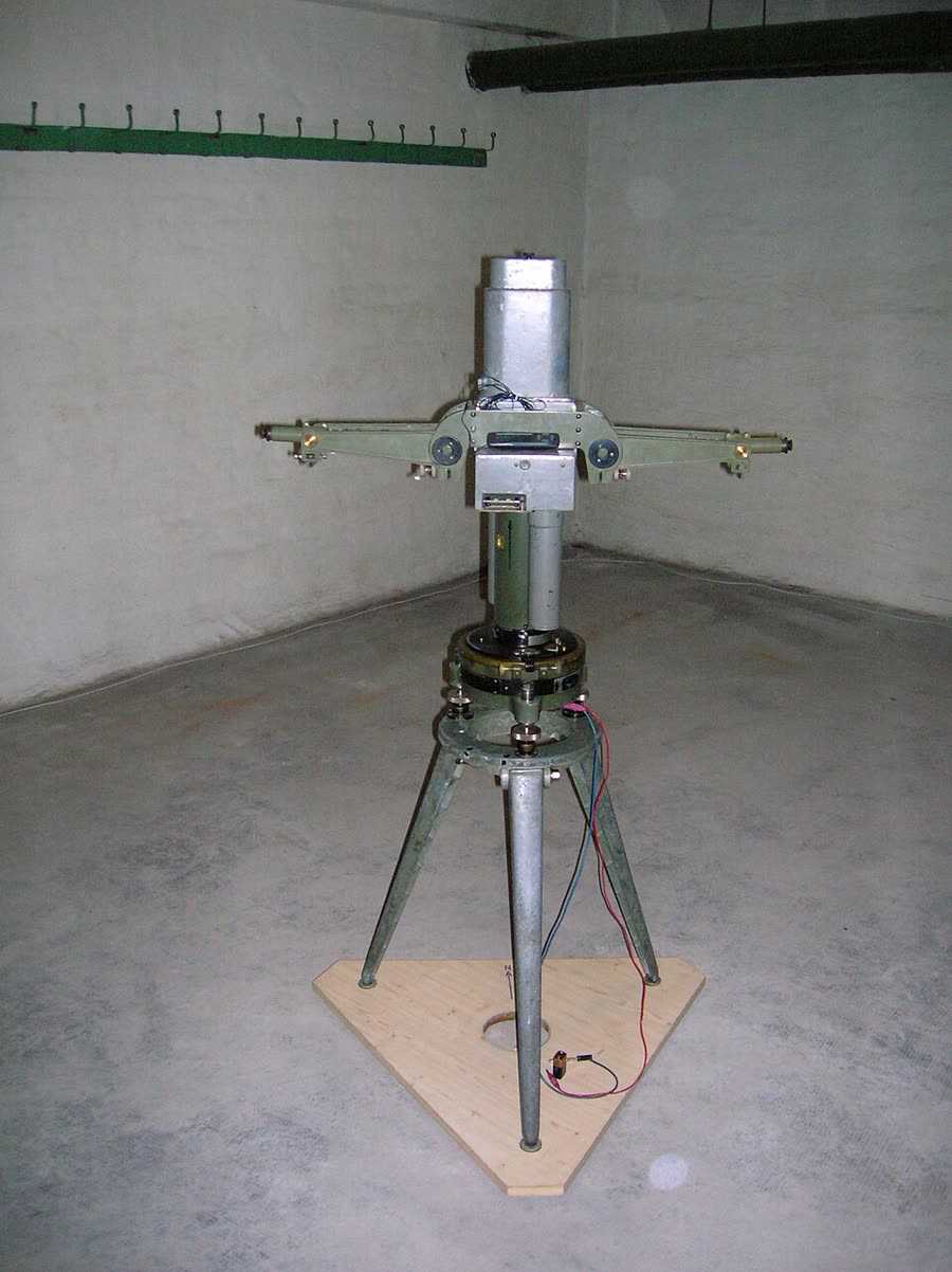 An Eötvös torsion balance: a long horizontal beam suspended from a fine wire inside a protective housing.