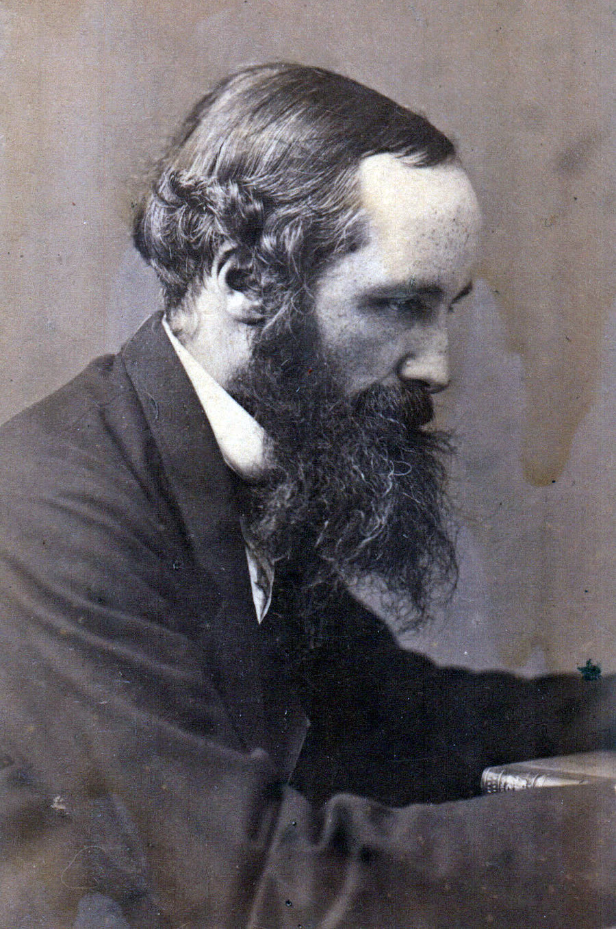 Photographic portrait of James Clerk Maxwell, seated, in dark Victorian dress with a full beard.