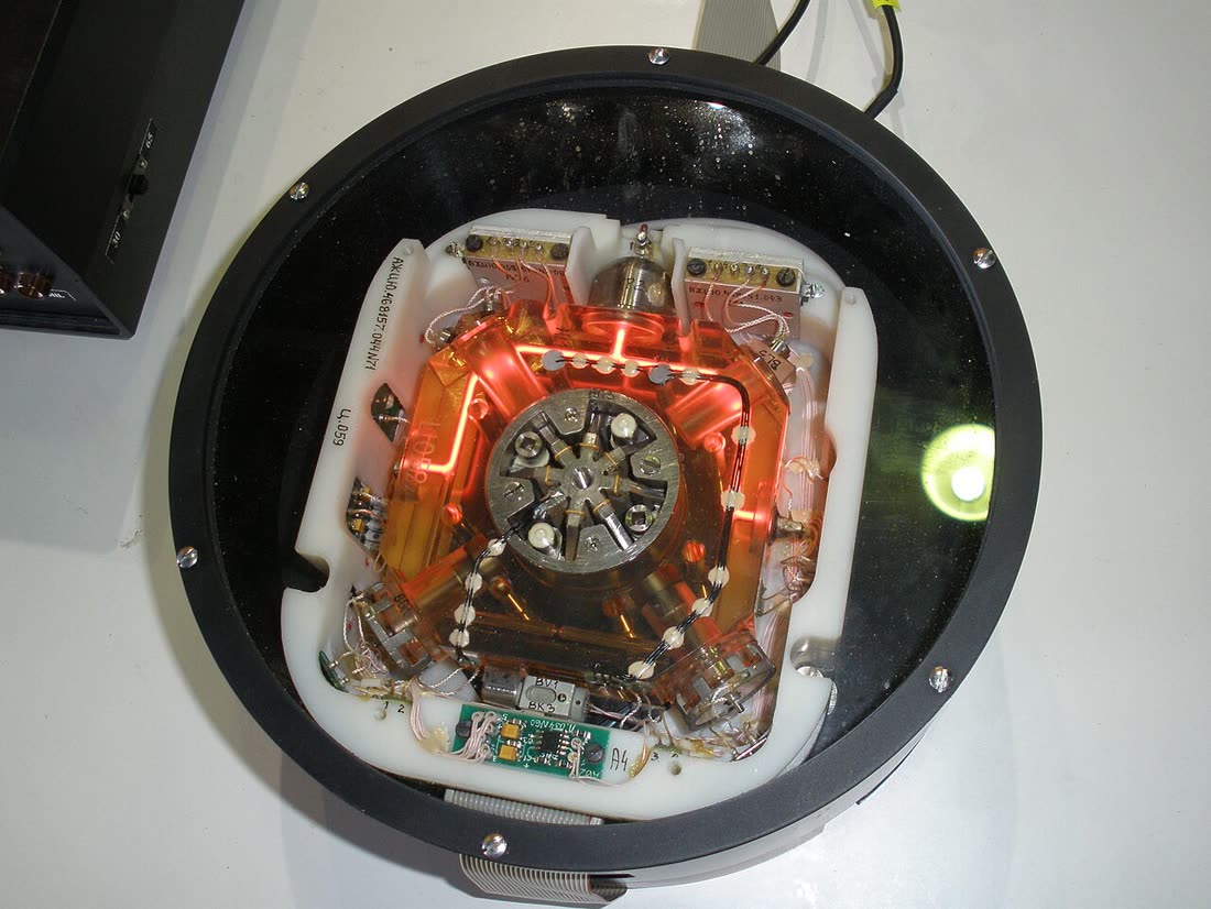 A modern ring laser gyroscope, a triangular block of glass with laser paths, on display.