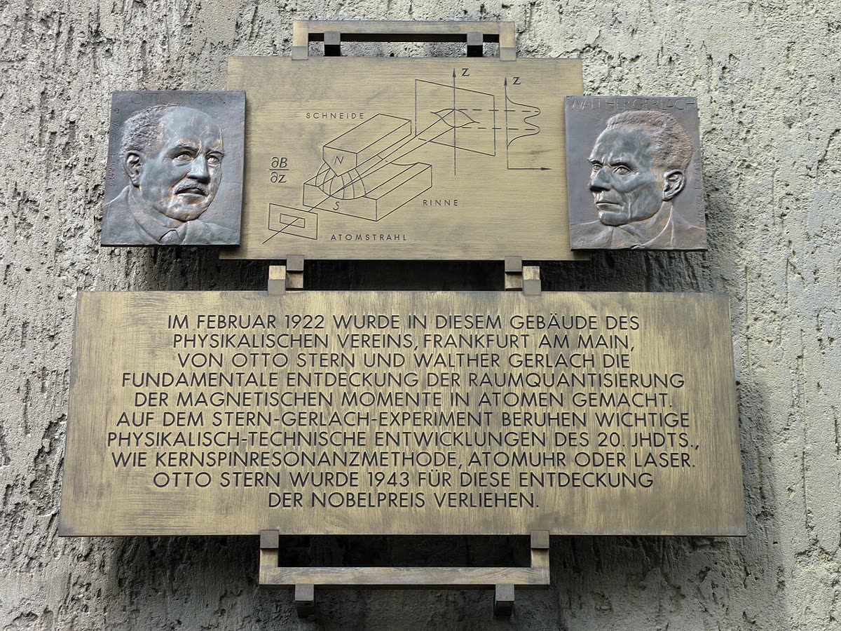 A commemorative plaque in Frankfurt showing the Stern–Gerlach apparatus and a reproduction of the postcard sent to Bohr.