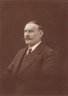 A photographic portrait of John Newlands in later life, bearded, in a dark coat.